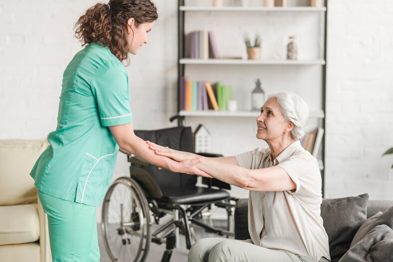 Betreuerin hält die Hände einer Seniorin