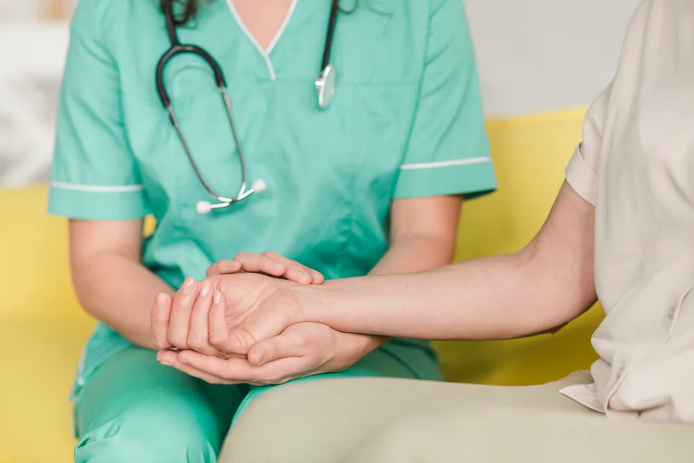 Diplomierte Pflegerin misst den Puls einer Patientin